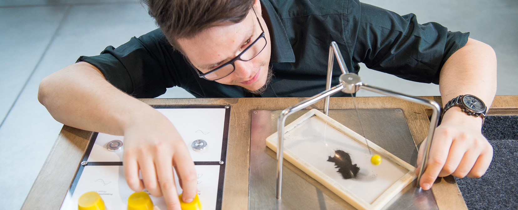 Ujęcie z góry, widać stolik i różne elementy na nim. Człowiek je ogląda.