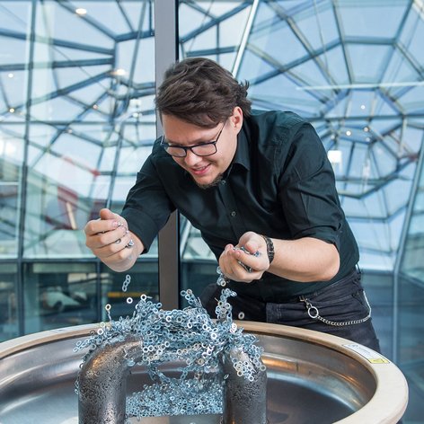 Na zdjęciu widać animatora, który eksperymentuje przy eksponacie "Magnetyczny most".