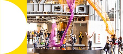  Zwiedzający bawią się w interaktywnym eksponacie unoszącym kolorowe tkaniny w powietrzu.