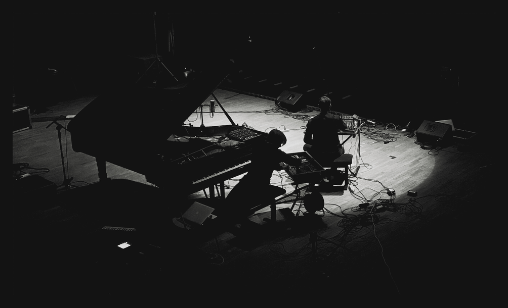 Czarno-białe zdjęcie artysty na scenie przy fortepianie