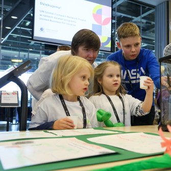Dwoje dzieci, nastolatek oraz dwie kobiety przy stole, na którym stoi terrarium