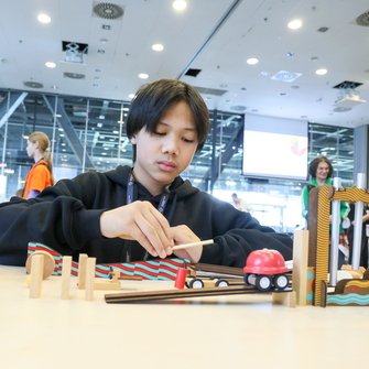 Nastolatek przy stole eksperymentuje z różnymi klockami