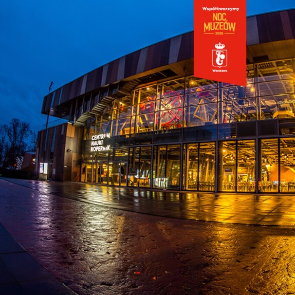 Zdjęcie przedstawia podświetlone wieczorem wejście do budynku Wystaw Centrum Nauki Kopernik. Na górze zdjęcia widać małą czerwoną aplę z warszawską syrenką i napisem "Współtworzymy Noc Muzeów 2025".