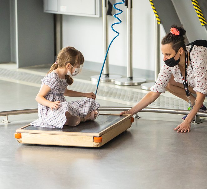 Dziewczynka z mamą eksperymentują przy eksponacie Latający dywan