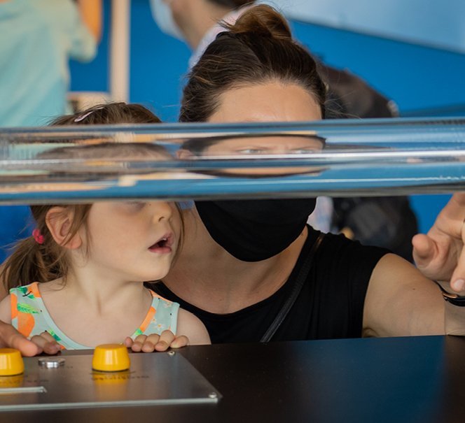 Dziecko z tatą przyglądają się jakiemuś eksponatowi w Strefie Eksperymentowania