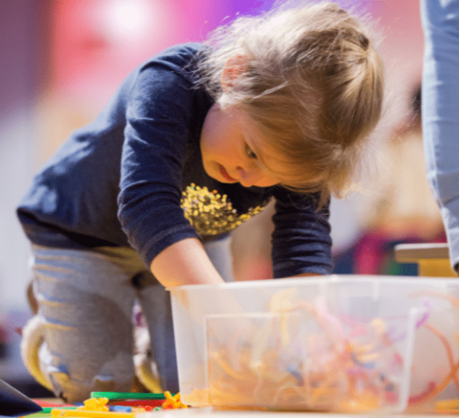 Dziewczynka pochylona nad pudelkiem pełnym kolorowych drucików