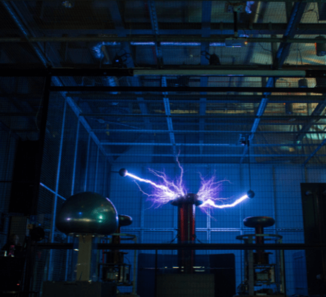 Wnętrzne Teatru Wysokich Napięć, między  generatorami widać dużą niebieską błyskawicę.