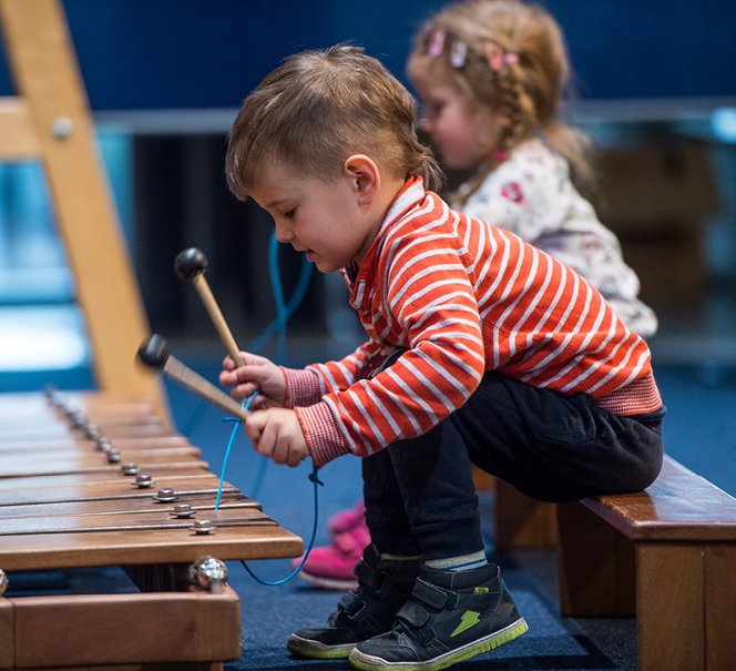 Chłopiec i dziewczynka siedzący przed wielkimi cymbałkami.
