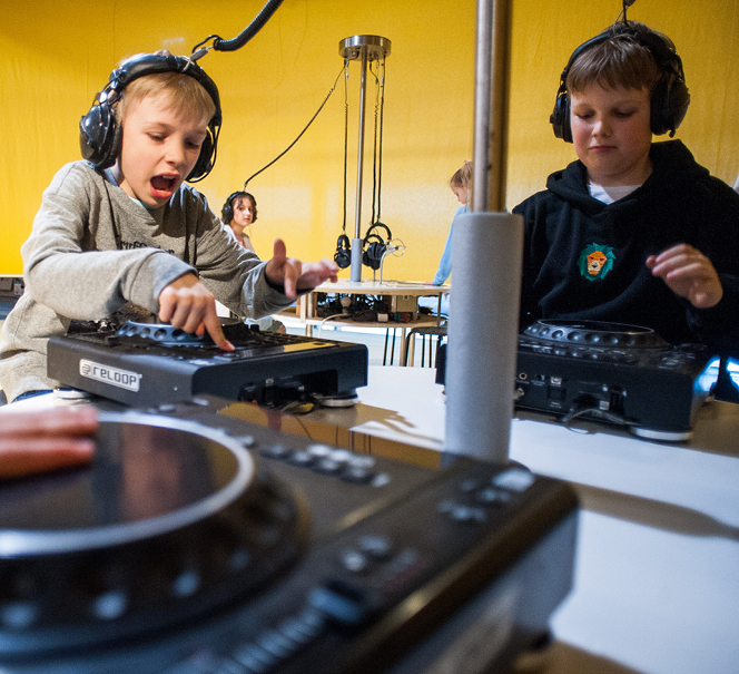 Dwóch chłopaków w słuchawkach skreczuje płyty jak didżeje.