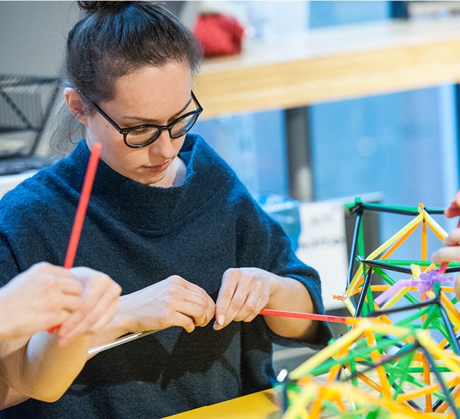 Kobieta ze skupieniem układająca coś ze słomek