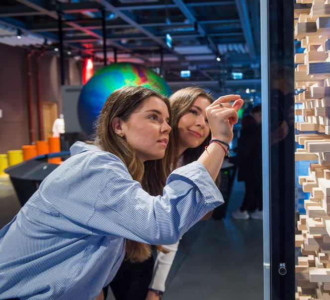 Zdjęcie dwóch osób wpatrzonych w eksponat przypominający grę jenga