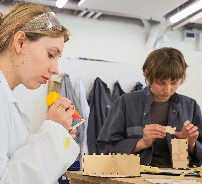 Dwie osoby nad drewnianymi elementami