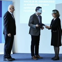 ALT do foty: Dyrektor Robert Firmhofer odbiera z rąk marszałek Senatu Małgorzaty Kidawy-Błońskiej, córki profesora Macieja Grabskiego, przyznawane przez FNP Wyróżnienie jego imienia za działania na rzecz społecznego rozumienia nauki w siedzibie Fundacji Batorego w Warszawie. Obok prezes zarządu Fundacji na rzecz Nauki Polskiej stoi Maciej Żylicz.